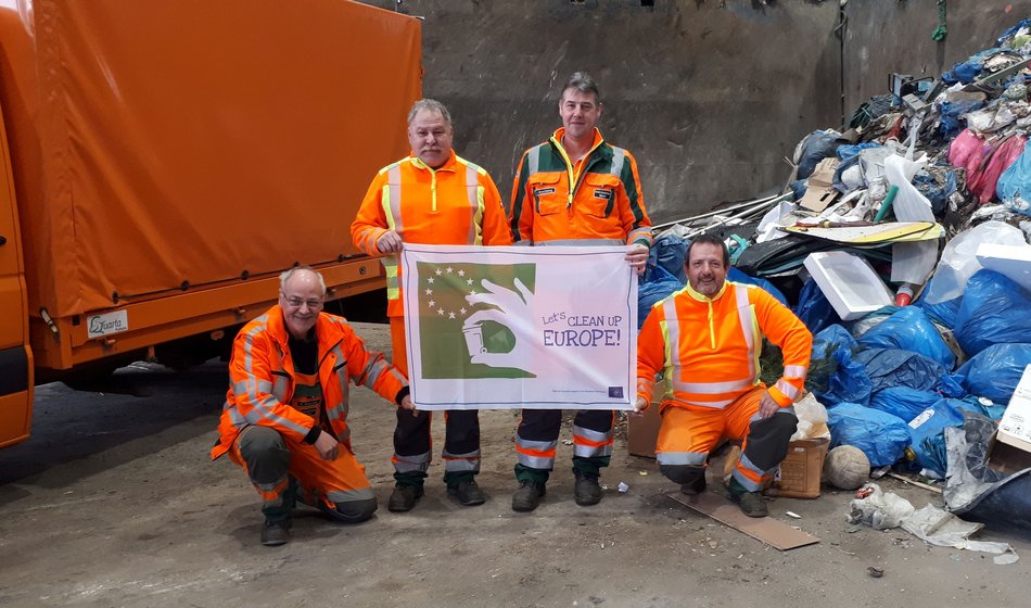 Mitarbeiterndes Kreisbauhofes halten die Let's clean up Flagge hoch